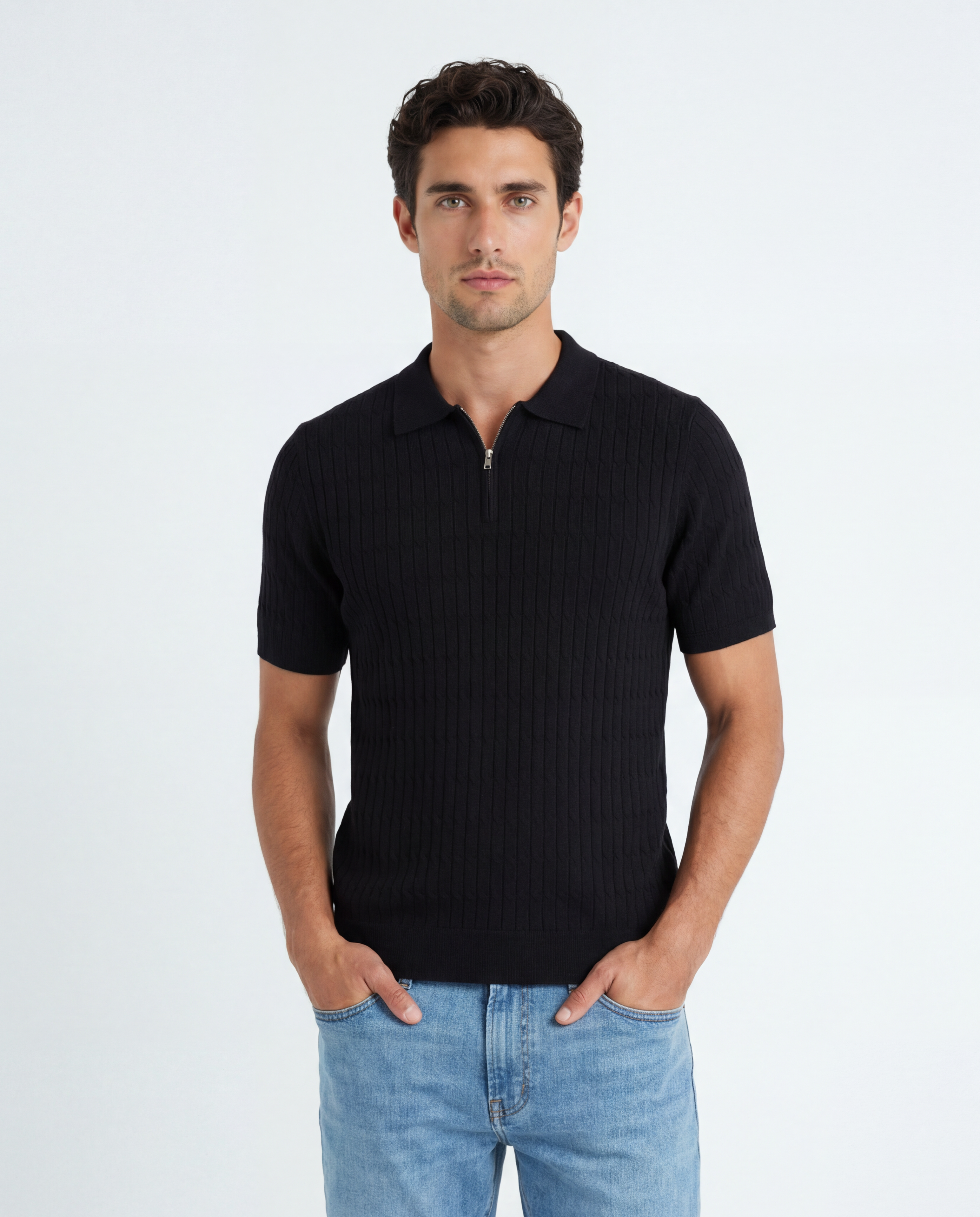 Man wearing a black polo shirt and light blue jeans on a white background